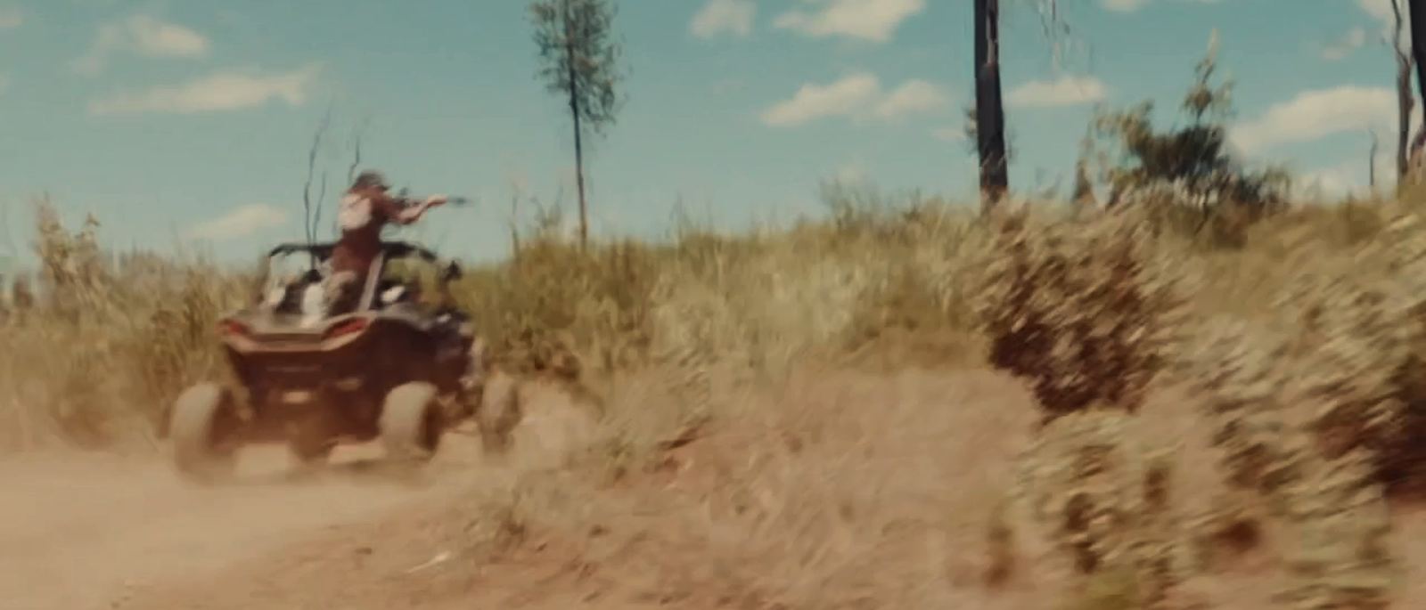 Side-by-side climbing a fire road, dust flying